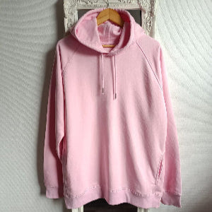 Pink hoodie hanging on a mirror against a white wall